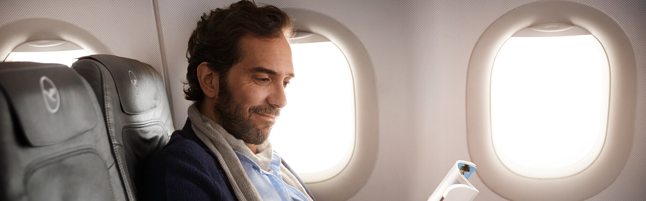 Passenger enjoying the flight in business class and reading a magazine